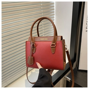 Detailed shot of red litchi texture handbag with brown handles and gold printed logo