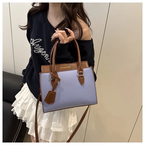 Detail of color-block PU leather handbag with purple body and brown strap handles