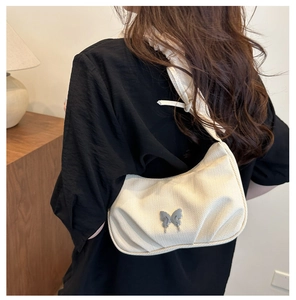Détail du sac nuage beige crème avec boucle papillon porté à l'épaule pour femme