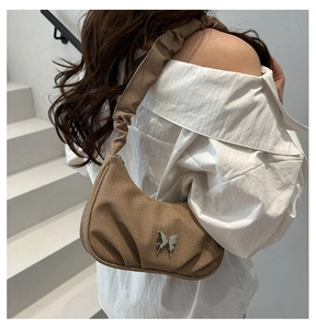 Close-up of brown crescent bag with silver butterfly and pleated shoulder strap