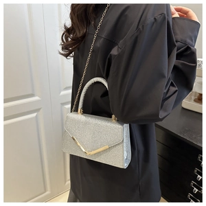 Close-up of silver glitter handbag featuring a gold V-shaped metal buckle and chain strap