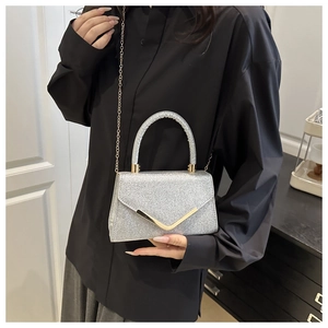 Silver sequin handbag with gold V-buckle and chain strap shown on a model