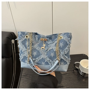 Detail of star-pattern denim tote bag featuring gold chain straps and deer charm