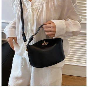Minimalist black matte leather handbag with gold twist lock shown on a model