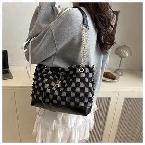 Detail of tweed checkered tote bag with gold chain strap and cute deer pendant accessory