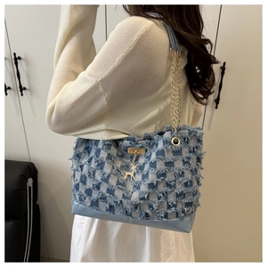 Detail of denim tote bag with frayed edges, checkered pattern and gold deer charm