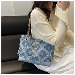 Detail of denim patchwork tote with white star prints and a golden deer charm
