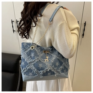 Detail of denim tote bag with frayed check pattern, star prints and gold deer charm