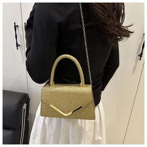 Detail of gold sequin clutch bag with metal V-flap and chain strap shown on model