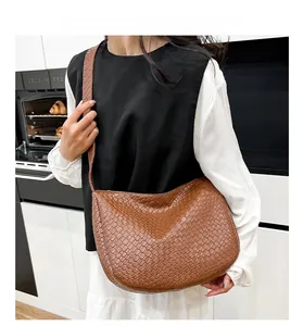 Detail of dark brown woven leather hobo bag with adjustable strap worn by a model