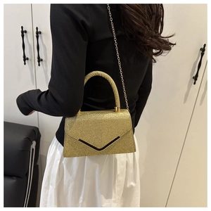 Detail of glitter gold crossbody bag with V-shaped metal trim and chain strap
