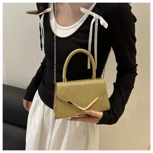 Detail of glittery dinner clutch bag with gold V-shape buckle and chain strap on model