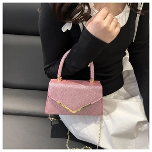 Pink glitter mini crossbody bag with gold V-hardware and chain strap shown on model