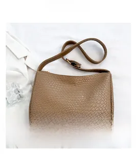 Detailed close-up of brown woven texture hobo bag on elegant white fabric background