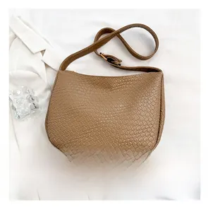 Detailed top view of a woven khaki leather hobo bag with a size comparison to a smartphone