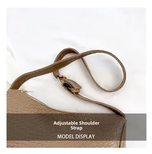 Detail of brown woven leather shoulder bag with adjustable strap and metal buckle
