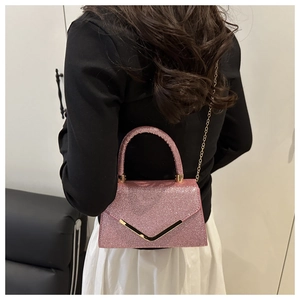 Pink sequin mini handbag with golden V-trim and chain strap shown on a model
