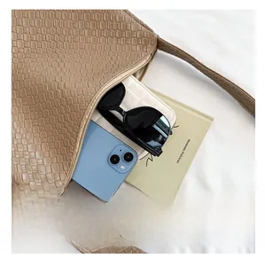 Interior view of brown woven tote bag showing smartphone, sunglasses and wallet