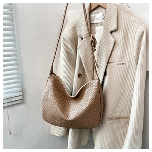 Detailed view of the khaki woven texture on a minimalist hobo-style shoulder bag