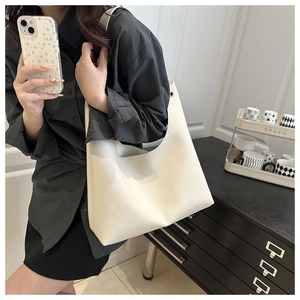 Détail du sac hobo en cuir grainé blanc cassé avec œillets argentés et bandoulière
