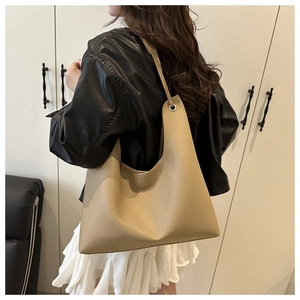 Détail du sac cabas en cuir grainé kaki montrant la bandoulière et l'œillet métallique