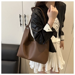 Détail du cuir grainé marron foncé et des œillets argentés sur un sac hobo chic