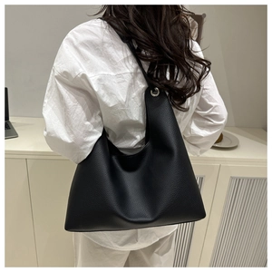 Détail du sac hobo en cuir grainé noir avec œillets argentés porté par un mannequin