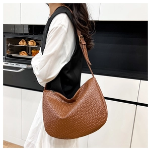 Brown woven texture hobo bag with adjustable strap worn by model in kitchen setting