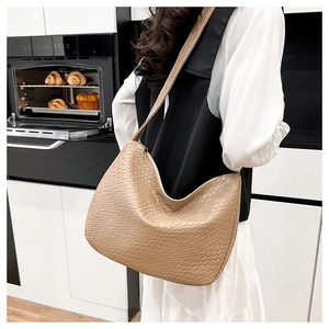 Detail of light beige woven texture on large crossbody tote bag in casual kitchen setting