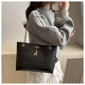 Detail showing wave woven texture of black tote with golden chain and deer pendant