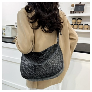 Detail of black woven hobo bag texture on model in minimalist coffee shop background