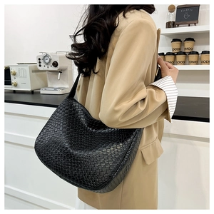 Detailed view of black woven hobo bag showing intricate texture and wide strap on model