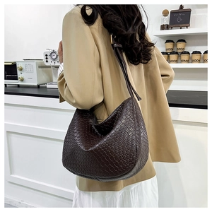 Detail of dark brown woven leather hobo bag with an adjustable strap on an elegant model