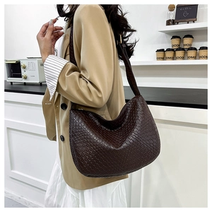 Detail of dark brown woven texture hobo bag worn by a model in a modern cafe setting