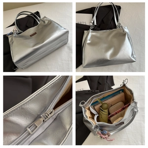 Detail view of large silver tote bag showing metallic texture, metal zipper and interior space