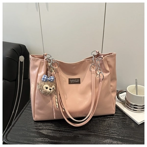 Detailed view of pink PU tote bag with metal chain strap and plush bear charm decoration
