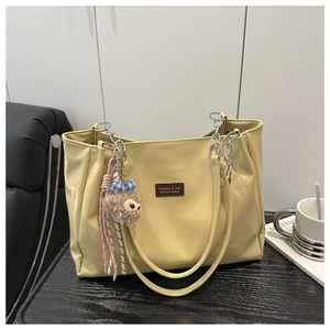 Close-up of yellow faux leather tote bag with brand label and metal chain strap details