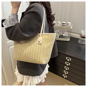 Detailed view of woven straw tote bag texture and elegant leather knot accent on shoulder strap