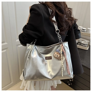 Detail of silver metallic tote bag with leather texture and cute plush bear charm