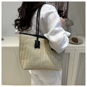 Large woven straw tote bag with black shoulder straps and rustic French beach vacation style