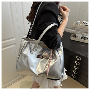 Detail of silver matte tote bag with chain strap and cute plush monkey charm