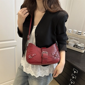 Red crocodile embossed hobo bag with silver studs and adjustable strap on a female model