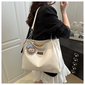 Detail of off-white tote bag featuring glossy faux leather with a cute bear charm