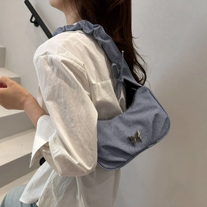 Sac à bandoulière en denim bleu avec boucle papillon argentée et bandoulière plissée chic
