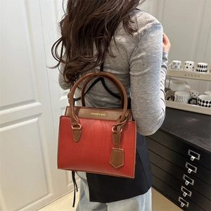 Fashionable red and brown patchwork leather handbag with minimalist top handle style