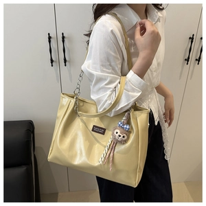 Detail of cream yellow tote bag with silver chain strap and ruffled side accents