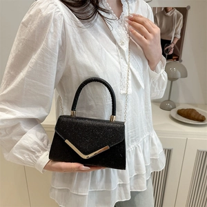 Sparkly black luxury handbag with golden V-clasp and chain strap shown from a front view