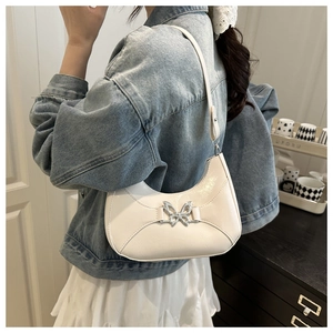 Sac hobo blanc chic en forme de croissant avec boucle papillon argentée porté à l'épaule