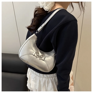 Détail du sac hobo argenté avec une boucle papillon métallique sur une bandoulière réglable