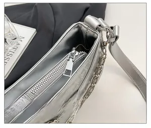 Detail shot of silver underarm bag with crocodile pattern and smooth metallic zipper